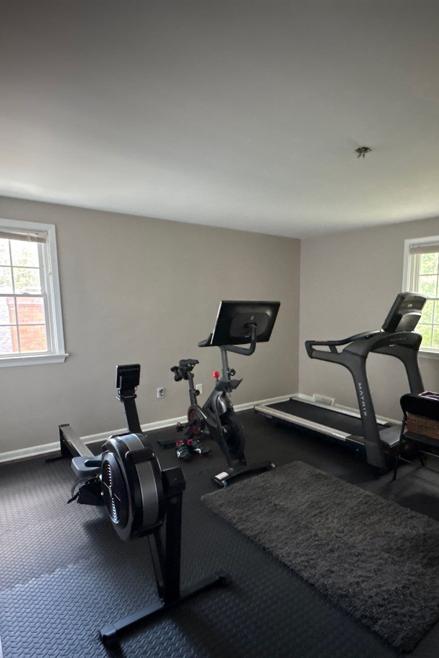 Home gym before repainting, with beige walls and fitness equipment, photographed prior to interior painting by Best Buy Painting in Cleveland, Ohio.