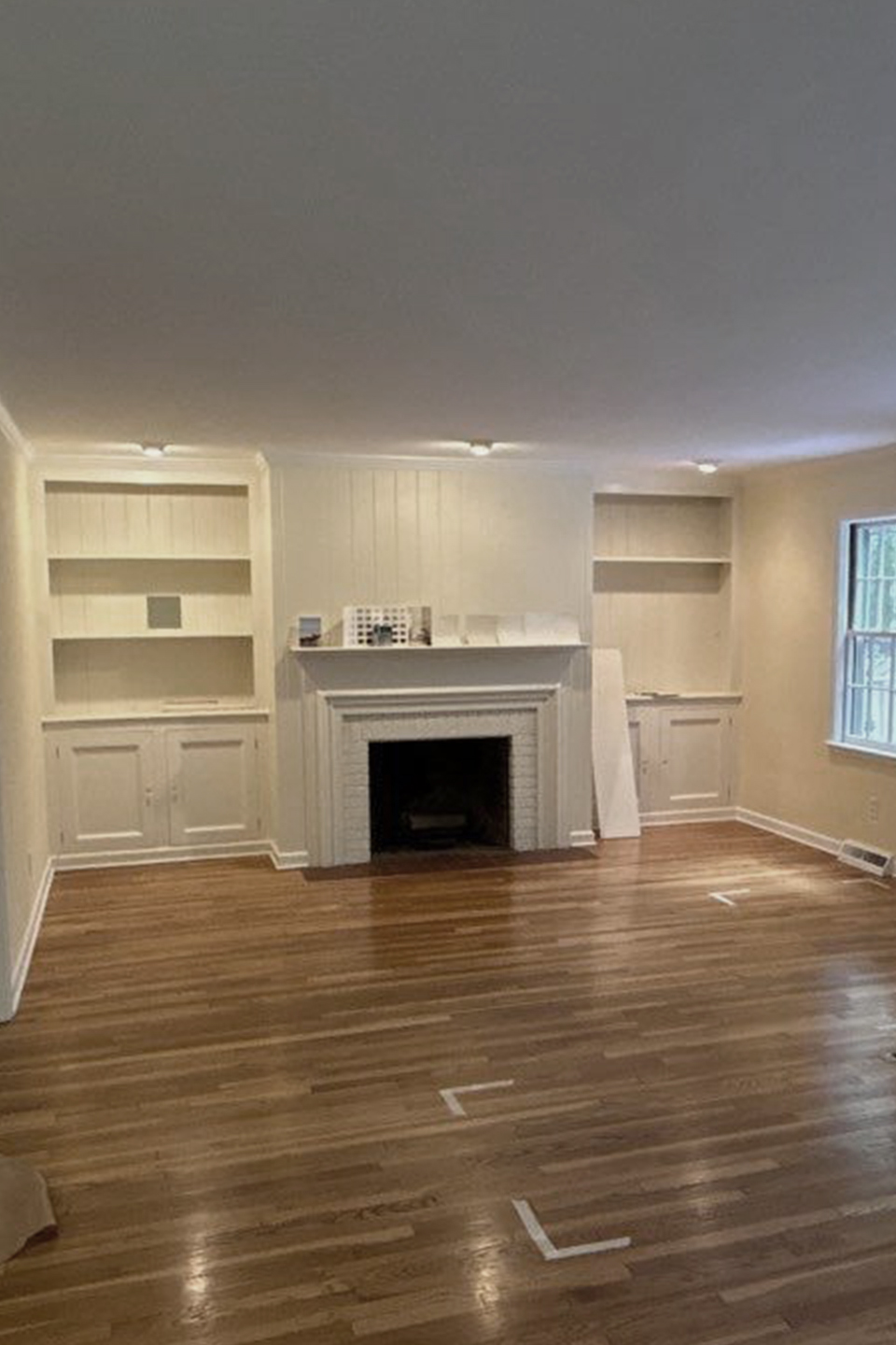 Living room before painting, showing yellow walls and white built-in shelves, photographed prior to repainting by Best Buy Painting in Cleveland, Ohio.