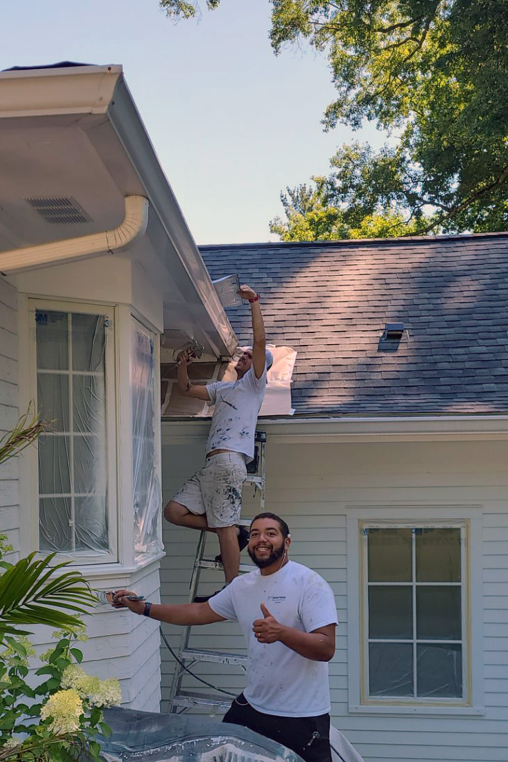 Two professional painters from Best Buy Painting working on a home exterior in Highland Heights, Ohio, applying white paint to siding and trim.