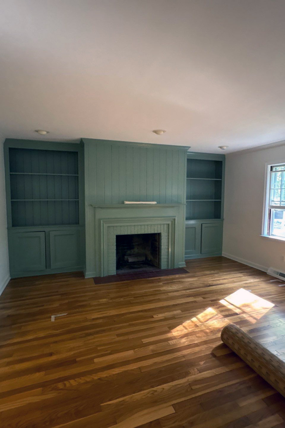 Living room after painting with sage green built-in shelves and fireplace surround, and white walls, completed by Best Buy Painting in Cleveland, Ohio.